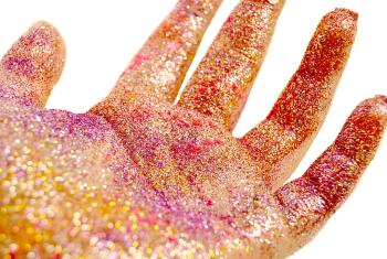 Colorful pink glitter coats someone's hand.  It is shiny, bright, and sparkly.