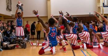 Harlem Globetrotter Sweet Lou II holds a baby from the crowd above his head during a reenactment of the famous "Lion King" scene at the Supreme Headquarters Allied Powers Europe Sports and Fitness Center, Belgium, Nov. 19, 2019.